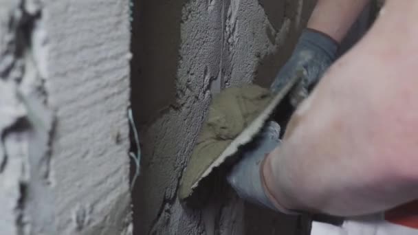 Hand eines Bauarbeiters verputzt Wand und Balken mit Zementputz auf der Baustelle — Stockvideo