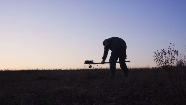 저녁에 삽을 가진 토양을 삽질 하는 노동자의 실루엣. — 비디오