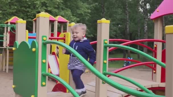 Anak itu dimainkan di taman bermain atau taman kanak-kanak. Anak itu menyenangkan bermain-main . — Stok Video