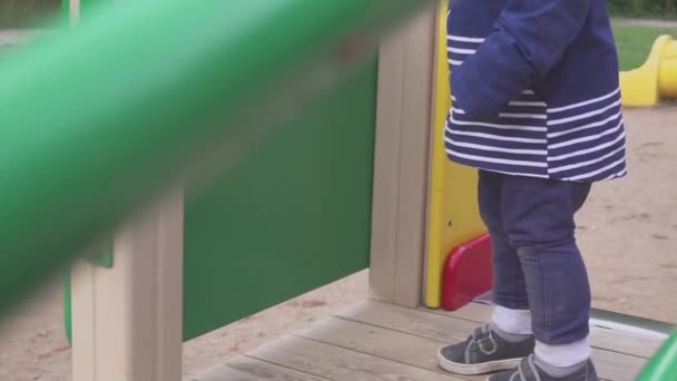 El niño se juega en un parque infantil en un parque o jardín de infantes. El niño es divertido para divertirse . — Vídeos de Stock