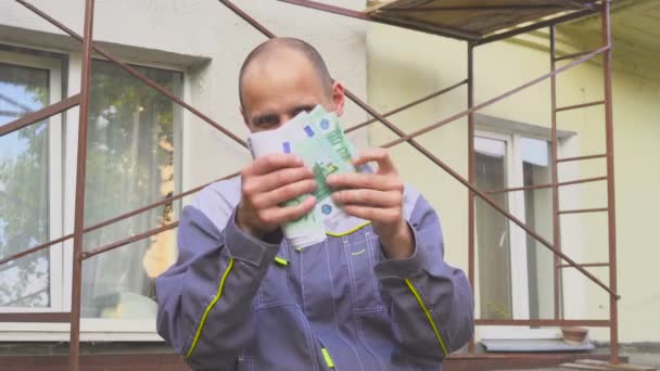 Emotivo felice costruttore con un sacco di soldi in euro all'aperto. concetto — Video Stock