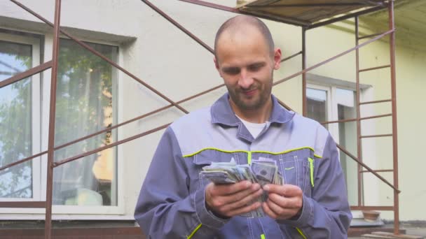 Builder counting his salary standing at the construction site — Stock Video