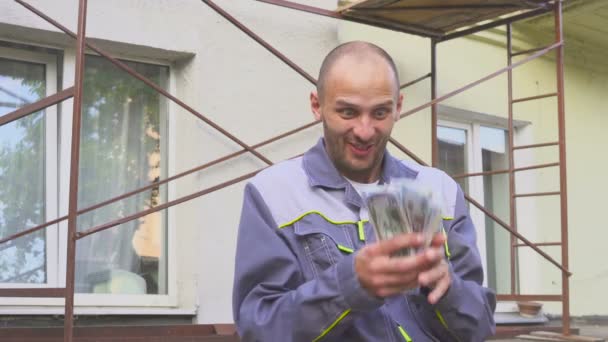 Счастливый строитель с большими долларовыми деньгами на улице. Концепция успеха в строительстве — стоковое видео