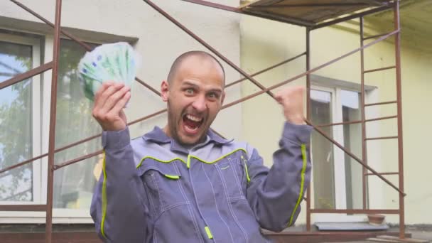 Känslomässiga glad builder med en massa euro pengar utomhus. — Stockvideo
