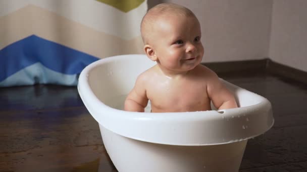 Bebê recém-nascido é coberto com gotas de água closeup brincando e sorrindo no banho — Vídeo de Stock