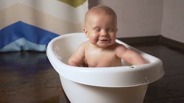 Newborn baby is covered with water drops closeup playing and smiling in the bath — Stock Video