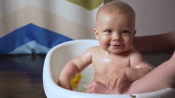 Bebê recém-nascido é coberto com gotas de água closeup brincando e sorrindo no banho — Vídeo de Stock