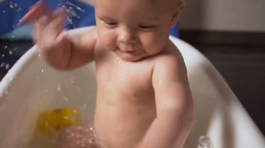 Yeni doğan bebek oynama ve banyoda gülümseyen su damla closeup ile kaplıdır