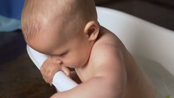 Bebê recém-nascido é coberto com gotas de água closeup brincando e sorrindo no banho — Vídeo de Stock