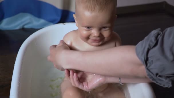 Bebê recém-nascido é coberto com gotas de água brincando e sorrindo no banho — Vídeo de Stock