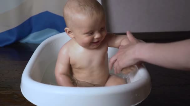 Neugeborenes Baby ist mit Wassertropfen bedeckt, die in der Badewanne spielen und lächeln — Stockvideo