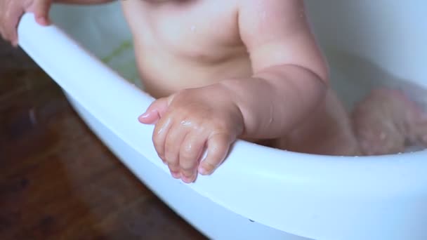 Bebê recém-nascido é coberto com gotas de água brincando e sorrindo no banho — Vídeo de Stock