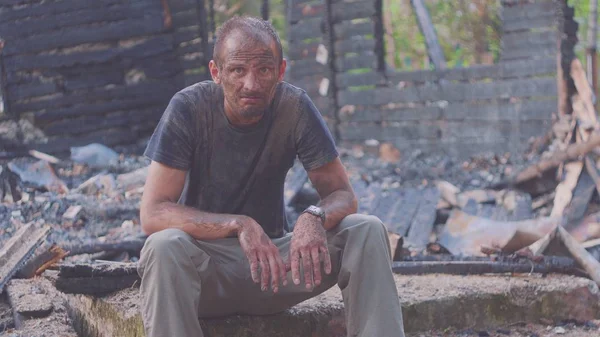 Portrait d'un homme triste sur le fond d'une maison brûlée, après un incendie. Conséquences de l'accident d'incendie. Ruines après un incendie désastre, concept de désespoir . Images De Stock Libres De Droits