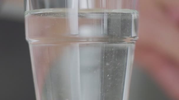 A valódi háttér előtt átlátszó üvegbe ömlött víz. Lassított mozgás — Stock videók