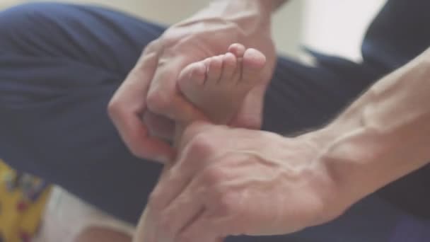 Närbild mamma gör fotmassage till en nyfödd pojke — Stockvideo