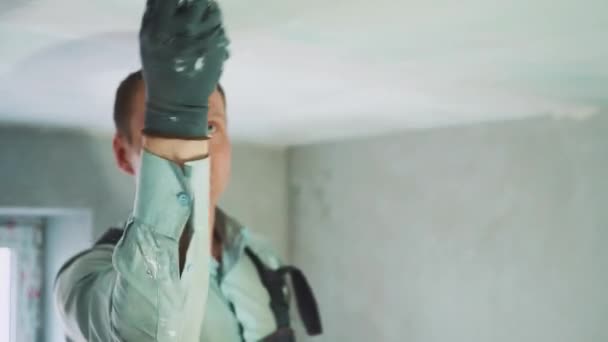 Молодой работник замазать потолок в комнате — стоковое видео