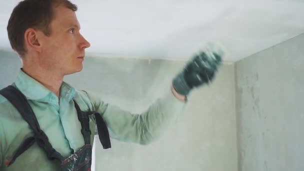 Молодий працівник зашпаклює стелю в кімнаті — стокове відео