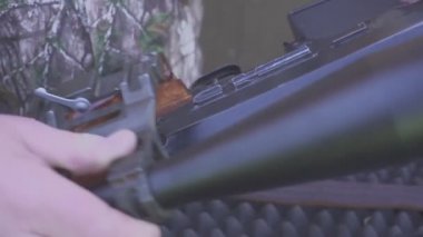 Avcı ya da keskin nişancının elleri bir av tüfeğine teleskopik bir görüş ekler.