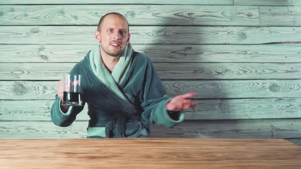 Cerveza y Sauna. Baño y spa. Hombre guapo en un albornoz está bebiendo cerveza y diciendo tostadas . — Vídeos de Stock