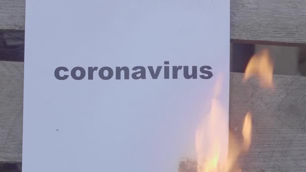 Φλεγόμενο χαρτί με τη μαύρη λέξη CORONAVIRUS. Έννοια του παγκόσμιου πολέμου. — Αρχείο Βίντεο