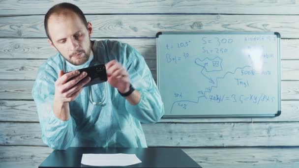 Spricht ein Arzt in Uniform mit einem Phonendoskop in einem Videochat mit einem Patienten. Coronavirus, Covid-19-Konzept — Stockvideo
