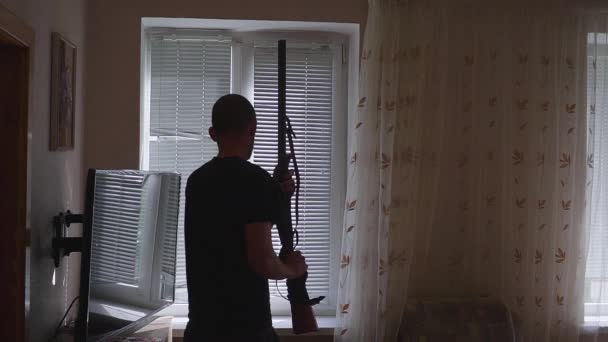 Ένας άντρας με όπλο, κοιτάζει από το παράθυρο. σωματοφύλακας και αυτοάμυνα έννοια. — Αρχείο Βίντεο
