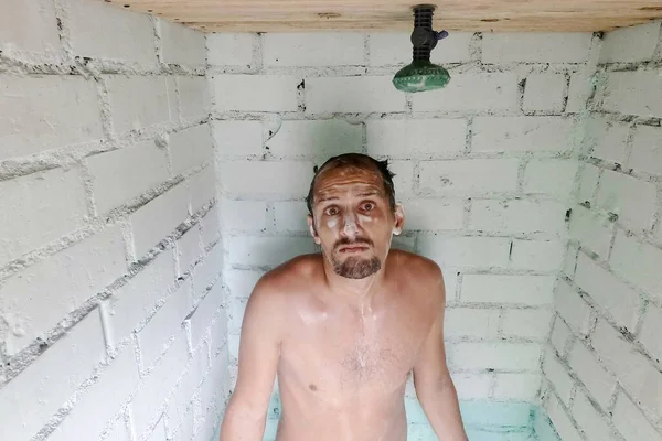 Inquiète caucasien moussait jeune homme après que l'eau dans la douche a été éteint. Panne de douche ou coupure d'eau chaude . Images De Stock Libres De Droits