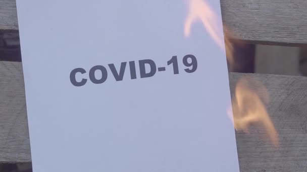 Het papier met het zwarte woord COVID-19 brandt, Wereldoorlogsconcept. slow motion — Stockvideo