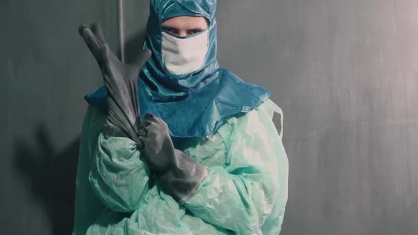 A man puts on a protective gown, a respirator and gloves. Personal protection and isolation concept — Stock Video
