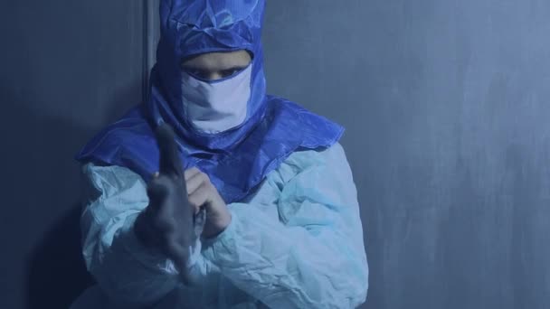 Een man trekt een beschermende jurk aan, een masker en handschoenen. Persoonlijke bescherming en isolatieconcept — Stockvideo