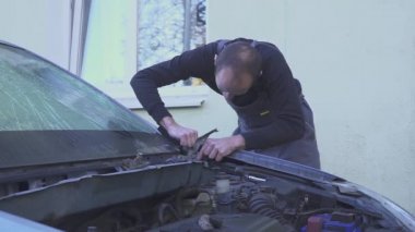 Erkek tamirci arabasını tamir ediyor. Kaybeden tamirci