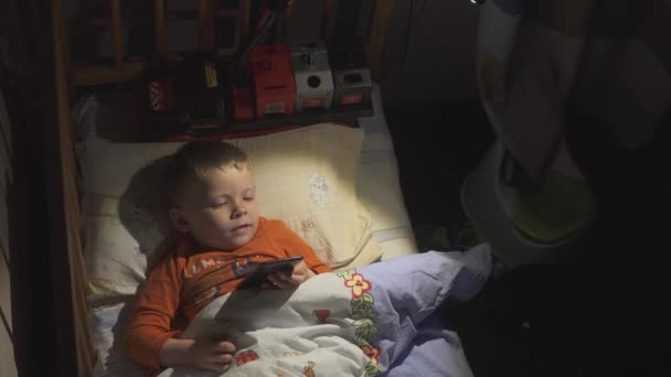 3 roky dítě chlapec pomocí smartphone v noci v posteli — Stock video