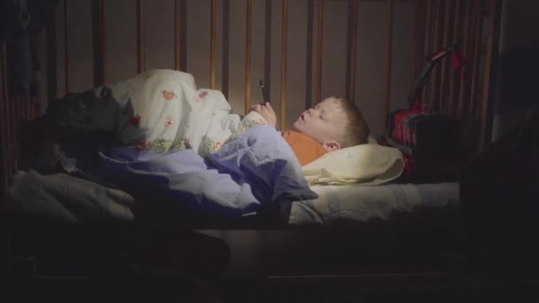 3 anos de idade criança boywatching desenhos animados em um smartphone à noite na cama . — Vídeo de Stock