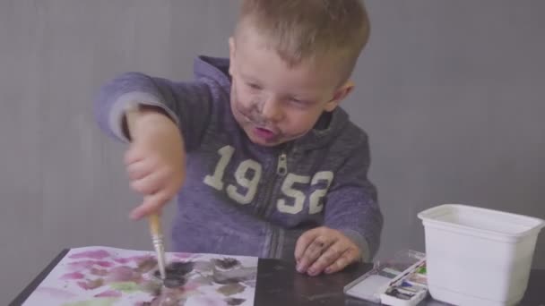 Ein lustiger Junge mit geschnittenem Gesicht zeichnet mit bunten Farben — Stockvideo