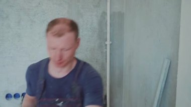 Erkek işçi duvarlara macun koyarak daireyi onarıyor. İnşaat evi.