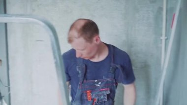 Erkek işçi duvarlara macun koyarak daireyi onarıyor. İnşaat evi.