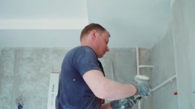 Erkek işçi duvarlara macun koyarak daireyi onarıyor. İnşaat evi.