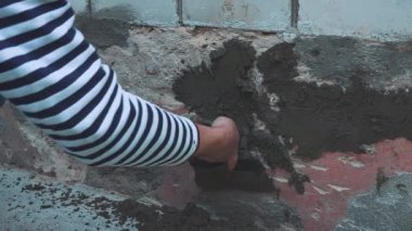 Erkekler duvar yalıtımı ve ev temeline mala sıva yapıyor. Kendin yap.