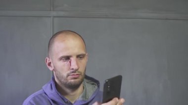 Baş yaralı erkek çalışan akıllı telefon kullanıyor.