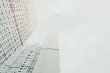 White contemporary residential skyscraper with a flying airplane sihlouette above clipart