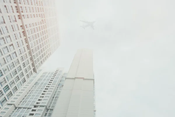 Arranha-céu residencial contemporâneo branco com uma sihlouette avião voador acima — Fotografia de Stock