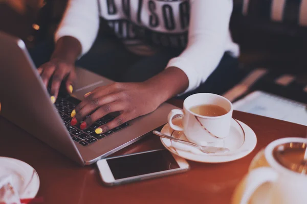 Zwarte handen met gekleurde nagels op laptop toetsenbord in café — Stockfoto