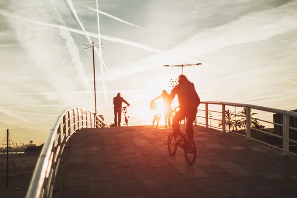 Três silhuetas humanas com bicicletas cruzando a ponte, Barcelona — Fotografia de Stock