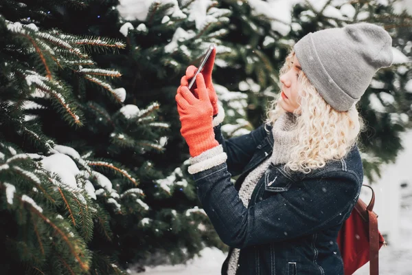 Rubia chica rizada haciendo foto en el teléfono inteligente, invierno —  Fotos de Stock