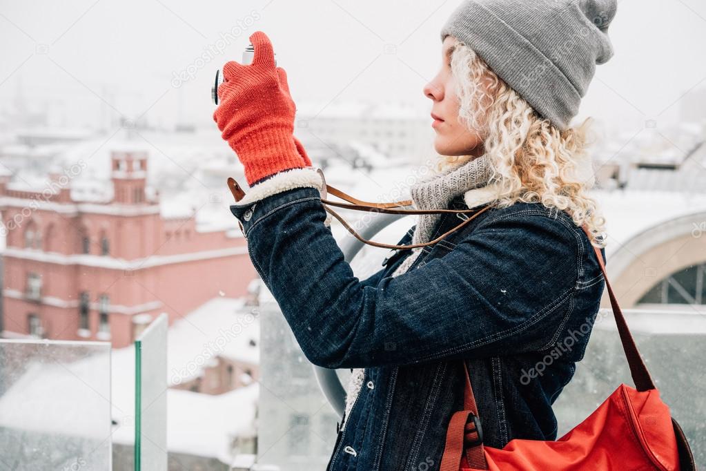 Blond curly girl shooting on film photo camera, winter