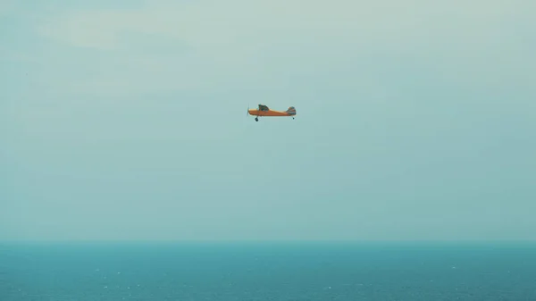 Avión de utilería naranja volando sobre el océano —  Fotos de Stock