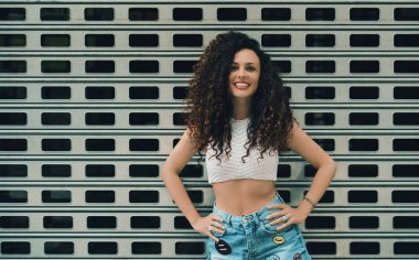 Kıvırcık gülümseyen esmer kız desenli duvar önünde