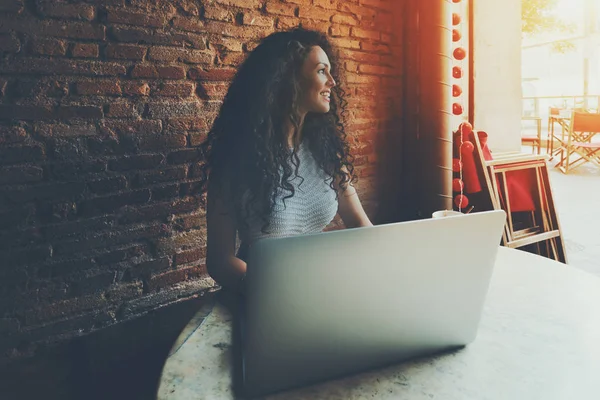 Curly smiling beautiful girl woking on laptop in cafe — Stock Photo, Image