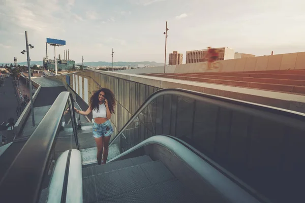 Beautiful curly girl is speaking on phone on escalator — Stock Photo, Image