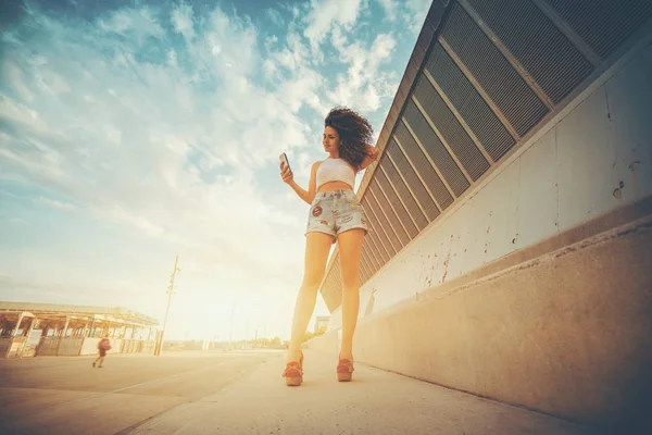 Young curly brunette girl texting message on her phone — Stock Photo, Image